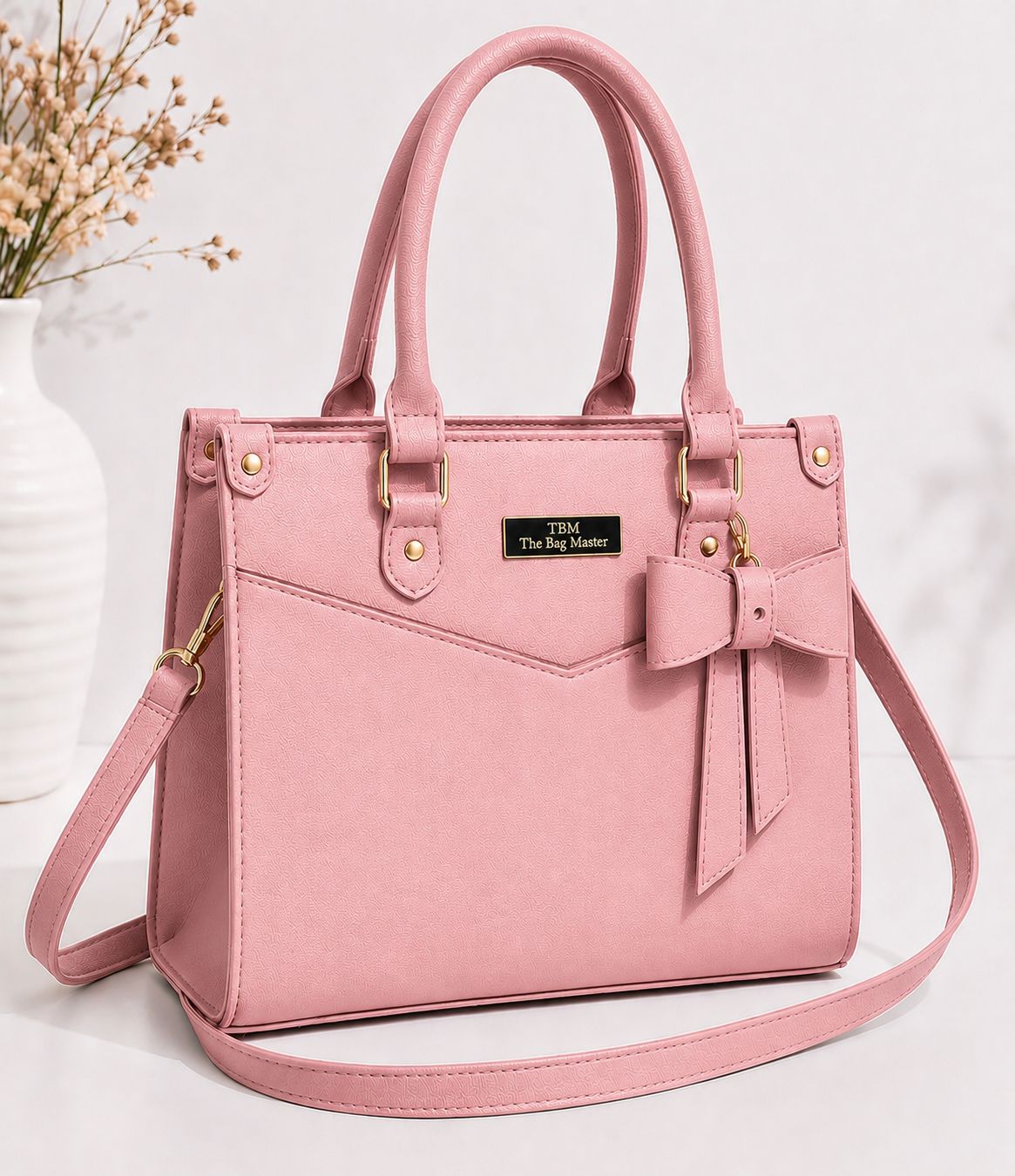 Pink handbag with a bow detail on a white background