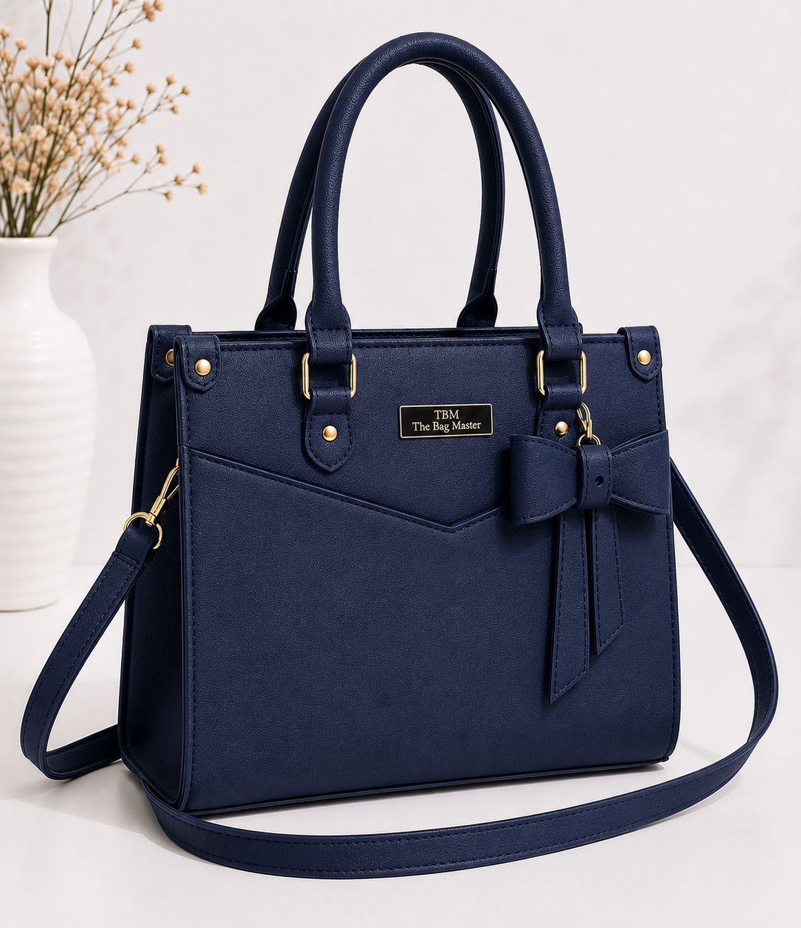 Navy blue handbag with a bow detail on a white background