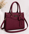 Maroon handbag with a bow detail on a white background