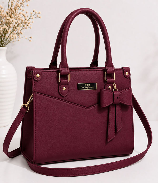 Maroon handbag with a bow detail on a white background