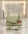 Light green handbag with cherry charm on a marble surface