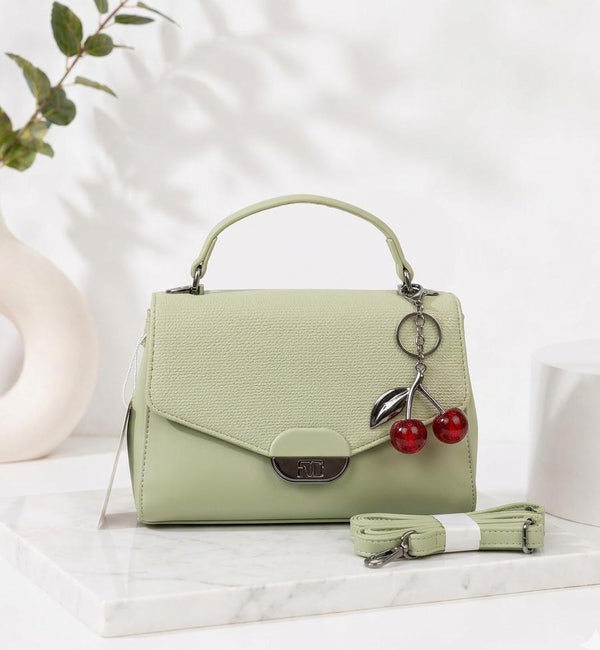 Light green handbag with cherry charm on a white surface