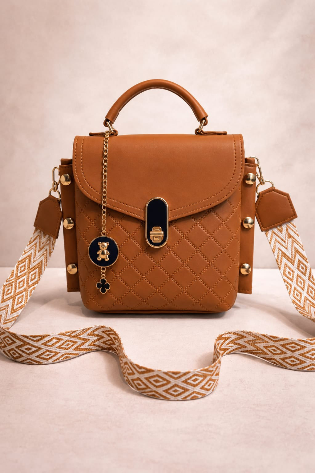 Brown quilted handbag with decorative strap on a beige background