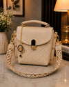 Beige handbag with decorative strap on a marble surface