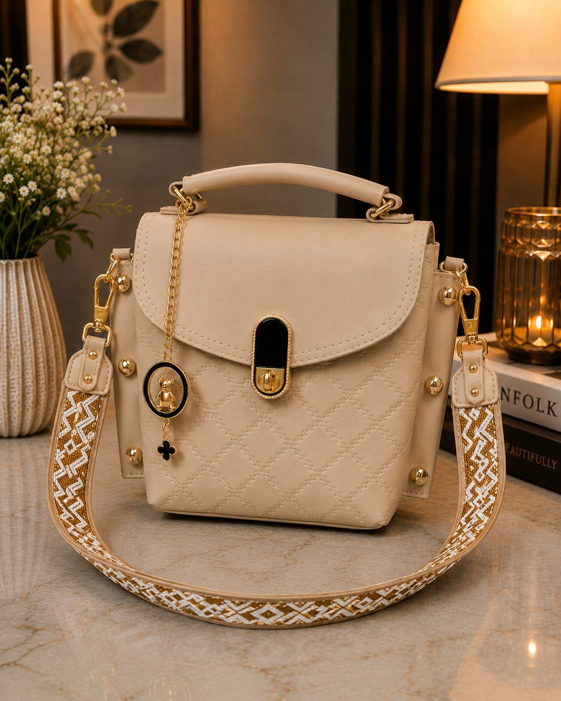 Beige handbag with decorative strap on a marble surface