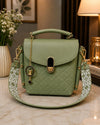 Green handbag with decorative strap on a marble surface