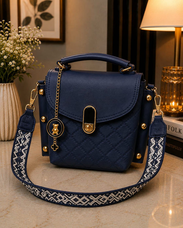 Navy blue handbag with decorative strap on a surface with a blurred background