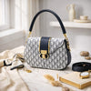 Designer handbag with black and gold accents on a marble surface with decorative items.