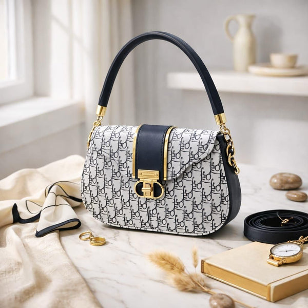 Designer handbag with black and gold accents on a marble surface with decorative items.