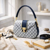 Designer handbag with blue accents on a table with accessories