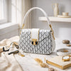 Patterned handbag with white handle on a light surface with accessories
