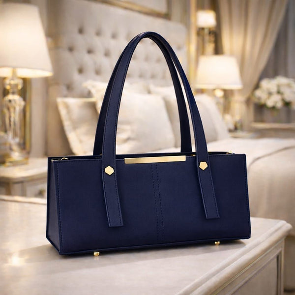 Navy blue handbag with gold accents on a table in a luxurious room.